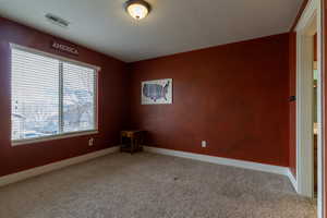 Empty room with carpet and a textured ceiling