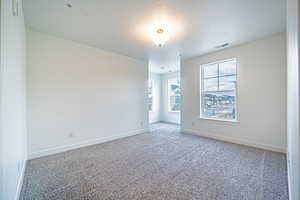 Carpeted empty room featuring baseboards, visible vents, and a textured ceiling