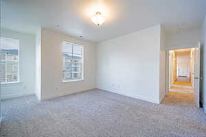 Empty room featuring light colored carpet, visible vents, baseboards, and a textured ceiling