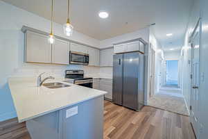 Kitchen featuring hanging light fixtures, light stone counters, visible vents, stainless steel appliances, and a peninsula