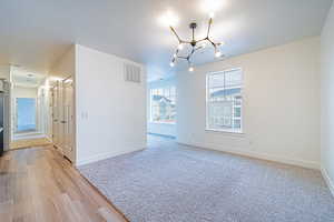 Empty room featuring visible vents, an inviting chandelier, baseboards, and a textured ceiling