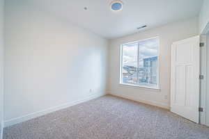 Unfurnished room featuring baseboards, visible vents, and carpet floors