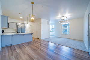 Kitchen with open floor plan, a breakfast bar area, pendant lighting, light countertops, and a chandelier