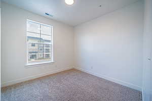 Empty room featuring visible vents, baseboards, carpet flooring, and a textured ceiling