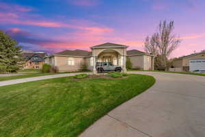 View of front of house with a front yard, curved driveway, and stucco siding