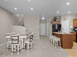 Kitchen with an island with sink, sink, a kitchen breakfast bar, and black fridge