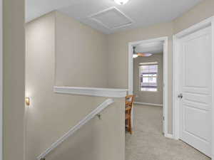 Hallway featuring light colored carpet