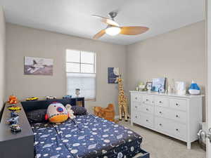 Carpeted bedroom featuring ceiling fan