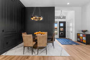 Dining room with baseboards, light wood finished floors, a chandelier, and recessed lighting