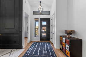 Entryway featuring visible vents, light wood-style floors, baseboards, and an inviting chandelier