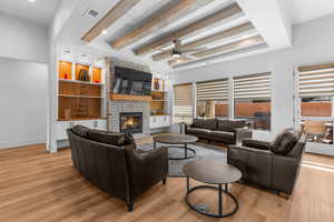 Family room with light wood-style flooring, visible vents, and a fireplace