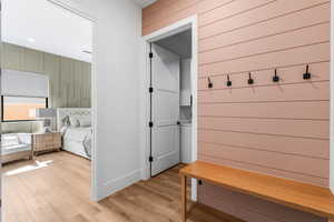 Mudroom featuring light wood finished floors and wood walls