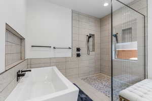 Primary Bathroom featuring a sink, a tile shower, and a soaking tub