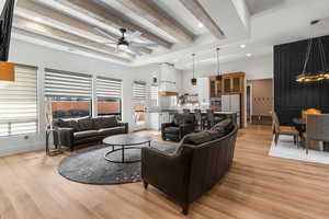 Living room with visible vents, light wood-style floors, beamed ceiling, and plenty of natural light