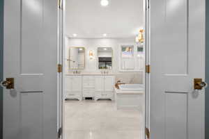 Bathroom featuring tile patterned floors, vanity, and a bath