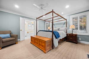 Bedroom with ensuite bathroom, ceiling fan, light colored carpet, and ornamental molding