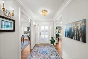 Foyer entrance with hardwood / wood-style floors and crown molding