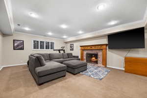 Carpeted living room featuring crown molding, a textured ceiling, and a fireplace