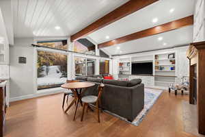 Living room with light hardwood / wood-style floors and lofted ceiling with beams