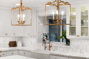 Kitchen featuring sink, white cabinets, decorative backsplash, and decorative light fixtures