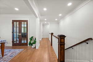 Hall with light hardwood / wood-style floors, french doors, and crown molding