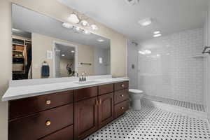 Bathroom with toilet, tiled shower, tile patterned flooring, and vanity