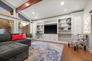 Living room with light wood-type flooring and vaulted ceiling with beams