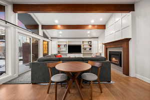 Living room with lofted ceiling with beams and light hardwood / wood-style floors