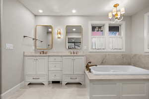 Bathroom featuring a tub, a chandelier, tile patterned floors, and vanity