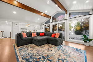 Living room with light hardwood / wood-style flooring, a chandelier, and lofted ceiling with beams