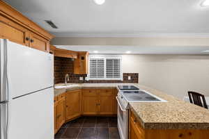 Kitchen featuring sink, white appliances, tasteful backsplash, and kitchen peninsula