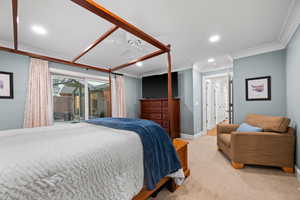 Carpeted bedroom featuring ceiling fan, ornamental molding, and access to exterior