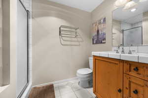 Bathroom featuring tile patterned flooring, toilet, vanity, and walk in shower