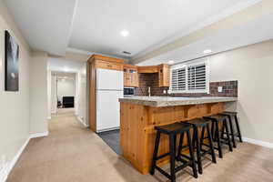 Kitchen featuring decorative backsplash, crown molding, white refrigerator, and carpet