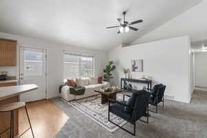 Living room with ceiling fan, light hardwood / wood-style flooring, and vaulted ceiling