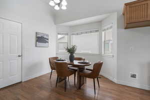 Dining room with dark hardwood / wood-style flooring and an inviting chandelier