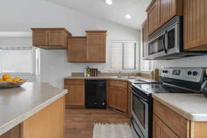 Kitchen featuring appliances with stainless steel finishes, sink, light hardwood / wood-style floors, and lofted ceiling