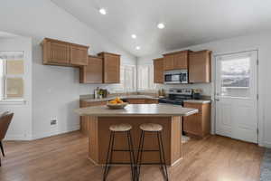 Kitchen featuring lofted ceiling, a kitchen island, stainless steel appliances, and light hardwood / wood-style floors