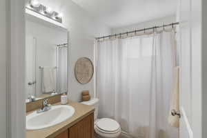 Bathroom with curtained shower, vanity, and toilet