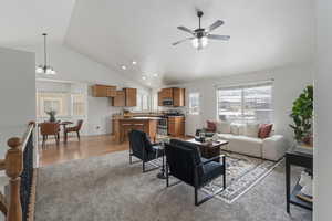 Living room featuring ceiling fan with notable chandelier, plenty of natural light, light hardwood / wood-style floors, and high vaulted ceiling