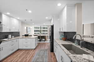 Kitchen featuring white cabinets, sink, black fridge, and kitchen peninsula