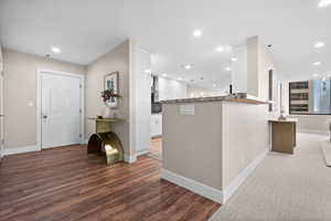 Kitchen featuring white cabinetry, kitchen peninsula, dark stone counters, and dark hardwood / wood-style floors