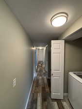 Hall featuring dark hardwood / wood-style flooring, washer / clothes dryer, and a textured ceiling