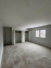 Unfurnished bedroom featuring multiple closets and light colored carpet