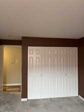 Unfurnished bedroom with light carpet and a closet