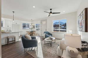 Living room with dark hardwood / wood-style floors and ceiling fan with notable chandelier