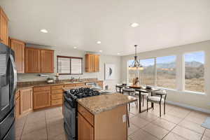 Large Kitchen featuring a center island, decorative light fixtures, refrigerator with ice dispenser, sink, and gas range oven