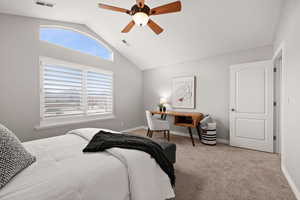 Carpeted bedroom featuring ceiling fan and lofted ceiling