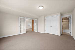 Unfurnished bedroom featuring french doors, carpet flooring, and a closet