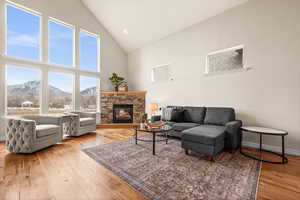 Living room featuring cedar hardwood / wood-style floors, high vaulted ceiling, a stone fireplace, and a mountain view